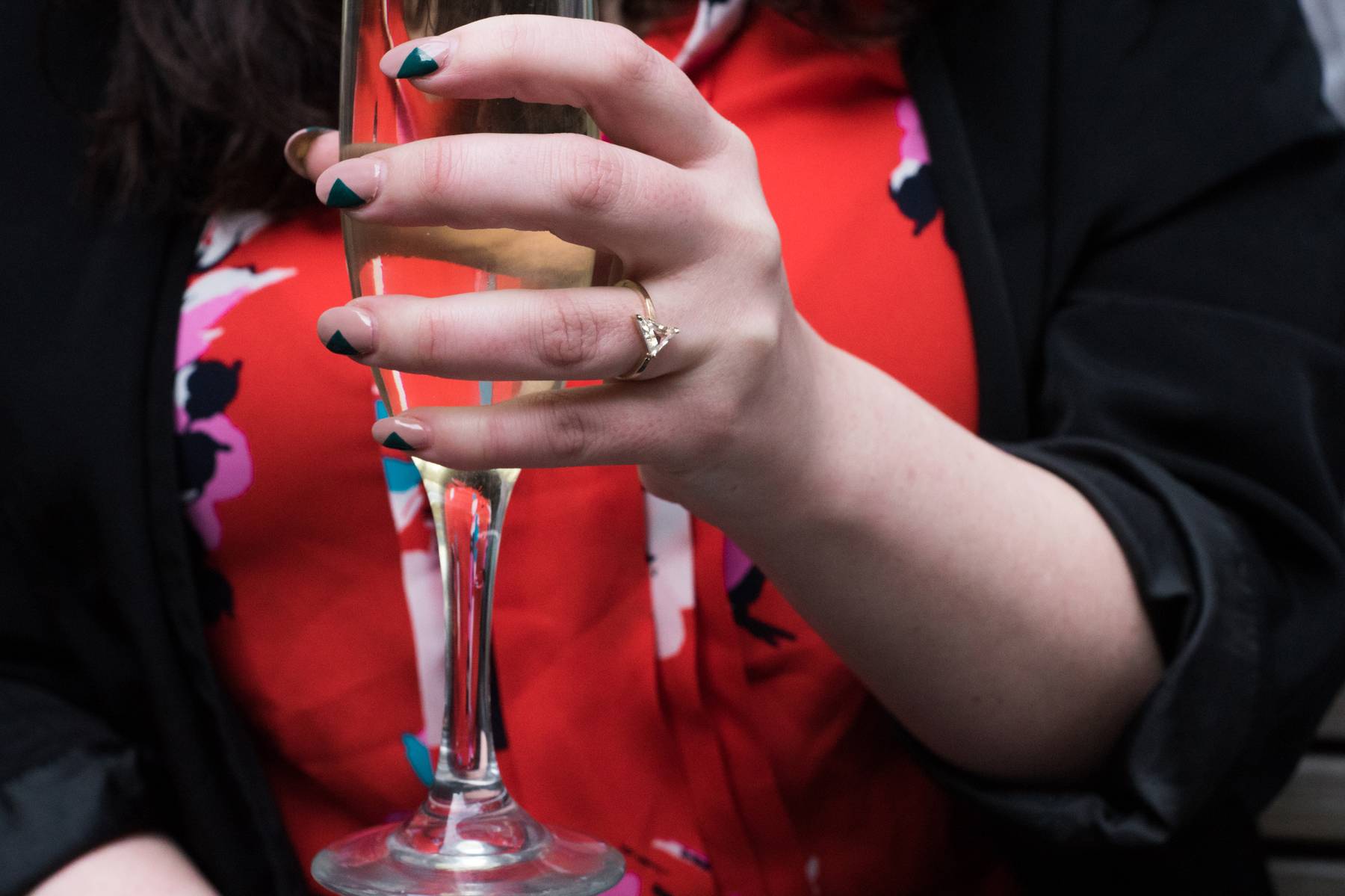 Michele’s ring-wearing hand holding champagne