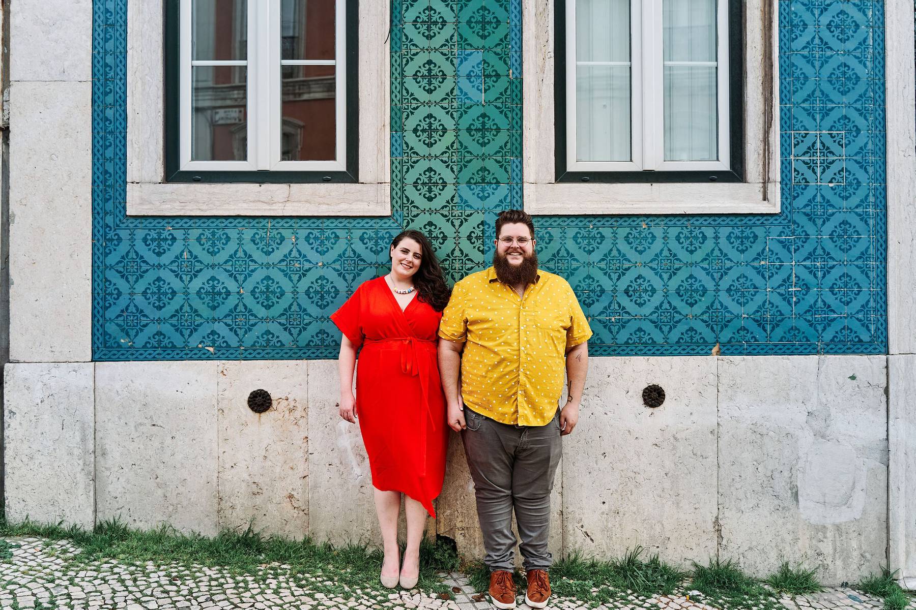 Michele &amp; Josh standing in front of a blue-green tiled wall